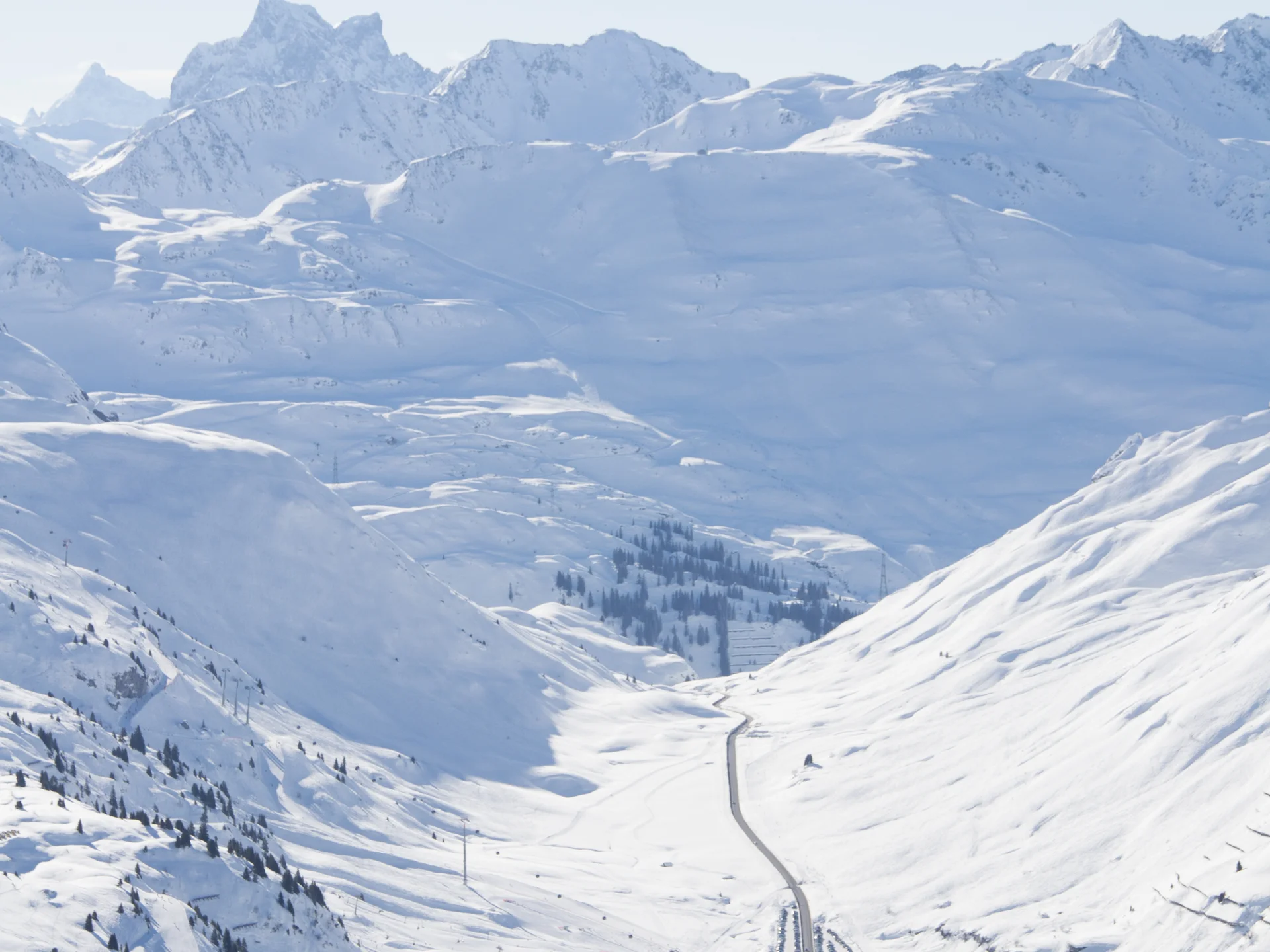 The journey to your hotel in Vorarlberg | Hotel Panorama Snow-covered mountain valley with a small settlement and road beneath high peaks