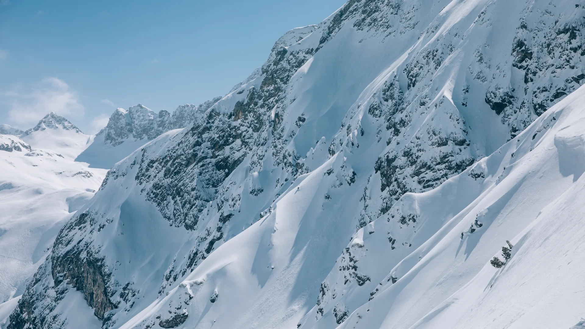 Snow-covered steep mountain peaks beneath a blue sky