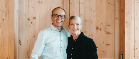 Smiling couple standing in front of a light wooden door