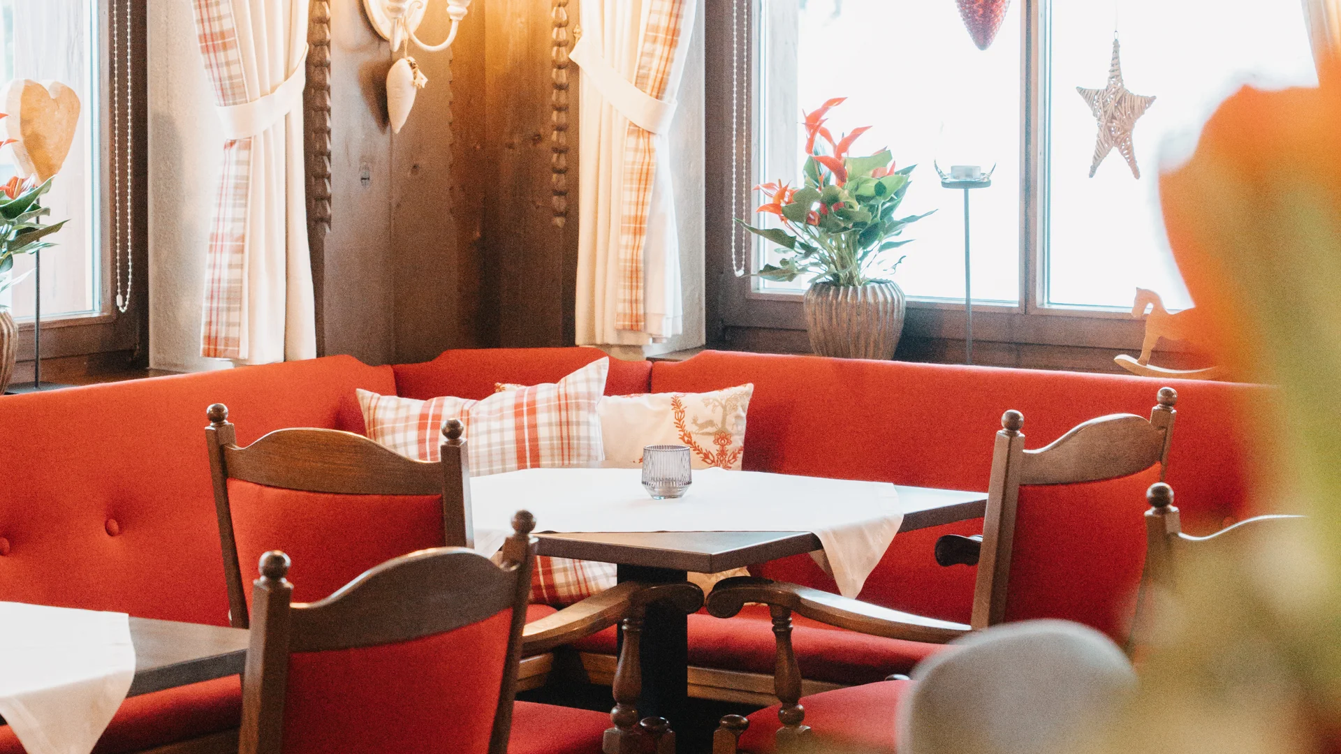 Picture gallery | Hotel Panorama in Lech am Arlberg Cosy dining room with red booth seating, wooden tables and stars hanging in the windows