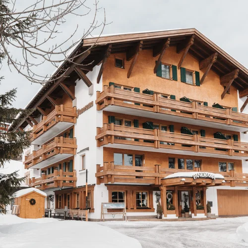 Inclusive services | Hotel Panorama in Lech am Arlberg Alpine-style building with wooden balconies and a snow-covered entrance