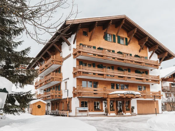 Inclusive services | Hotel Panorama in Lech am Arlberg Alpine-style building with wooden balconies and a snow-covered entrance