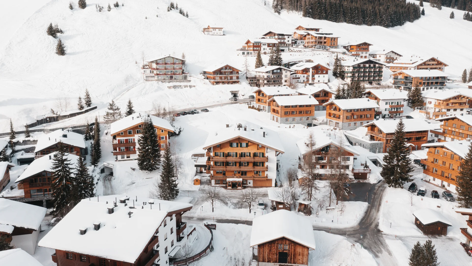 Picture gallery | Hotel Panorama in Lech am Arlberg Snow-covered mountain village with wooden houses and forested slopes, seen from above
