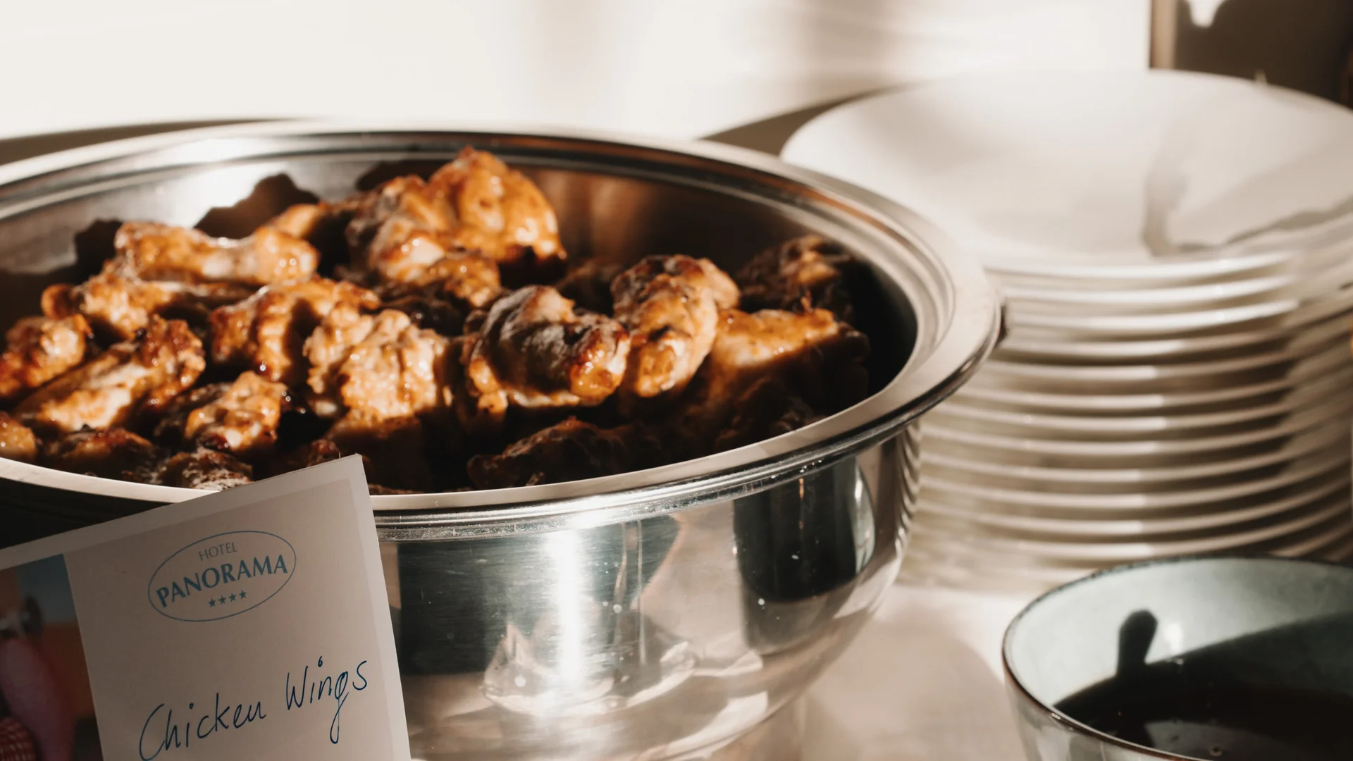 Picture gallery | Hotel Panorama in Lech am Arlberg Chicken wings in a buffet warmer beside a stack of plates and serving utensils