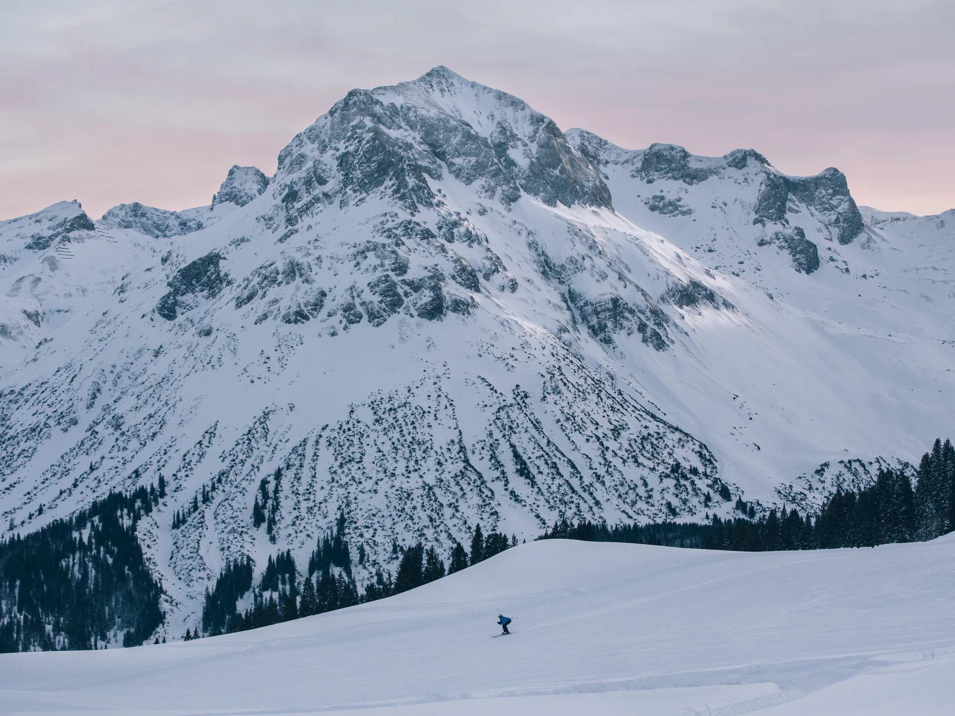 A ski holiday in Lech at Hotel Panorama A skier glides across a slope beneath snow-covered mountains