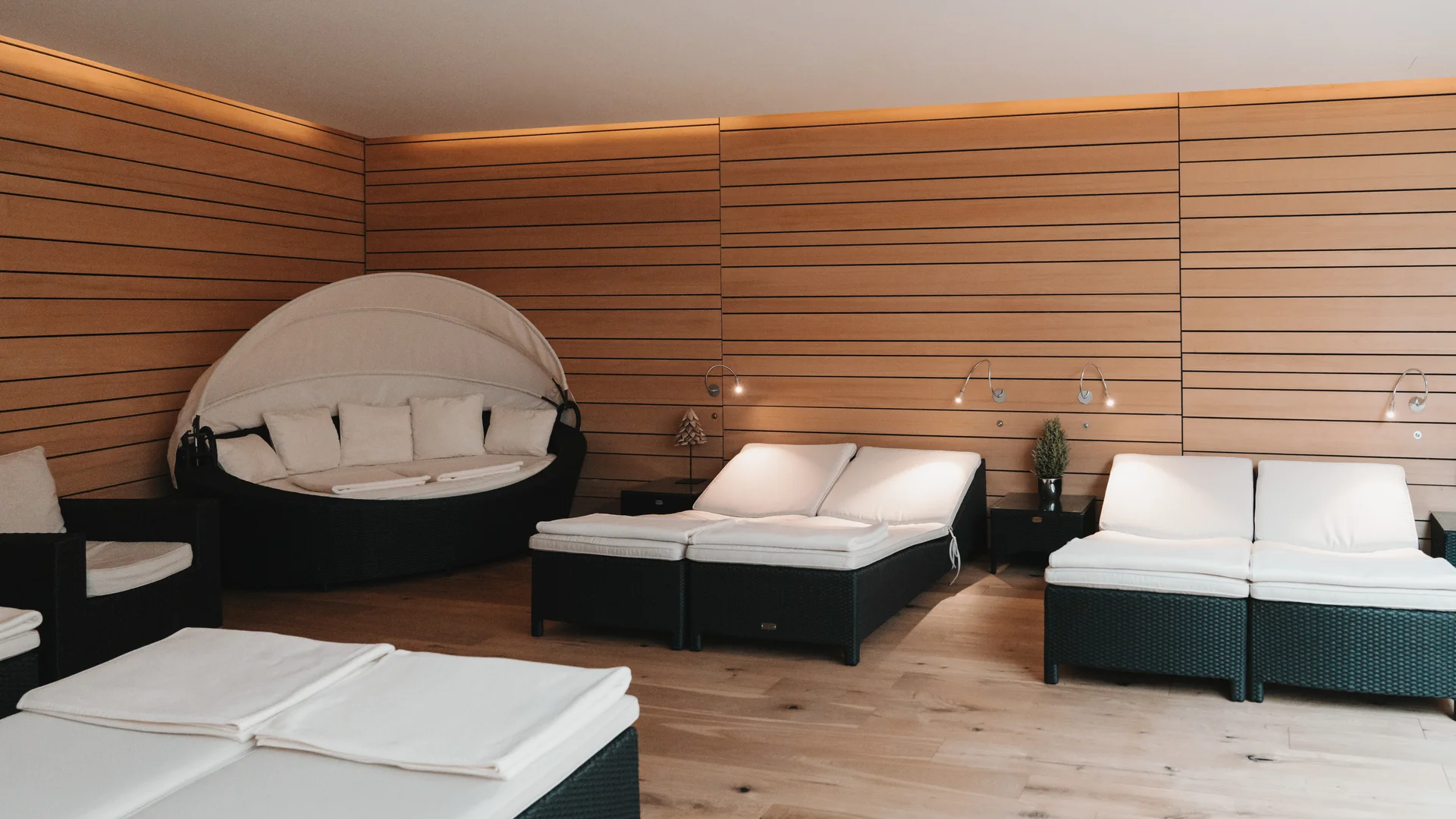 Picture gallery | Hotel Panorama in Lech am Arlberg Relaxation room with white loungers and a round cocoon daybed against wood-paneled walls