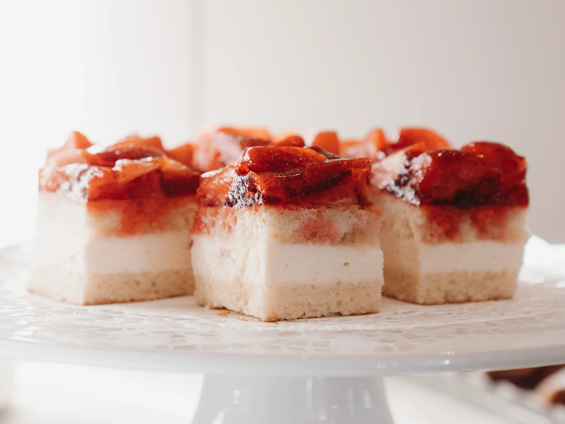 Mehrere Stücke Erdbeerkuchen mit Sahnefüllung auf einer weißen Etagere