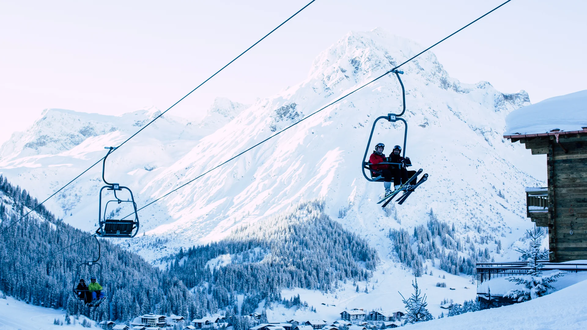 Picture gallery | Hotel Panorama in Lech am Arlberg Ski lift carrying skiers past a snowy mountain and a village in the valley