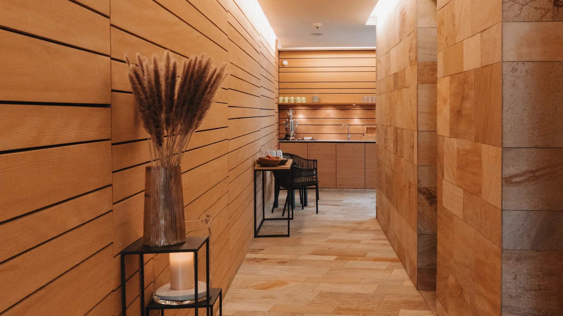 Picture gallery | Hotel Panorama in Lech am Arlberg Warm-toned corridor with wood paneling, stone flooring and a vase of dried flowers