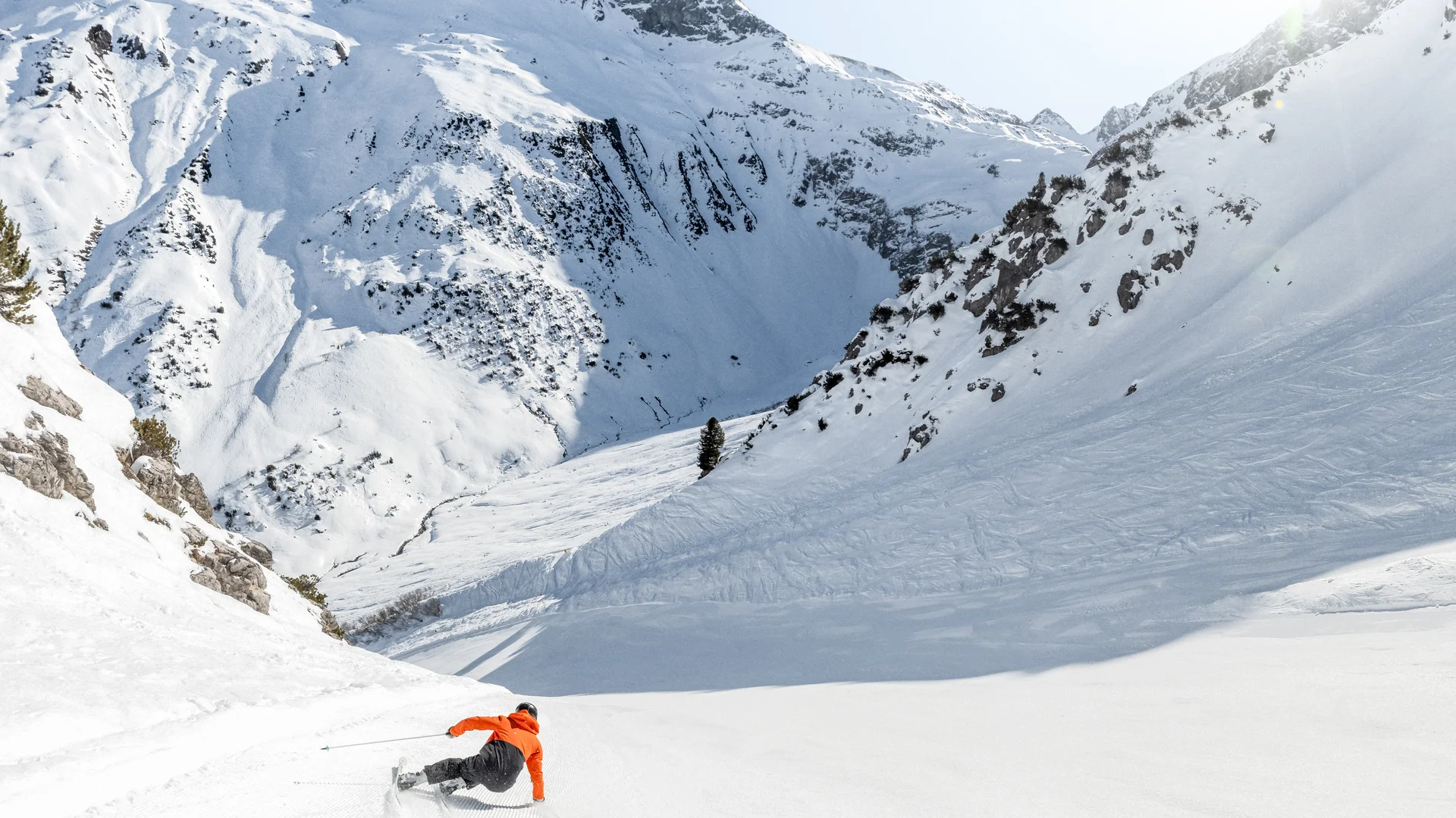 Picture gallery | Hotel Panorama in Lech am Arlberg Skier in an orange jacket descending a snowy slope beneath towering mountains