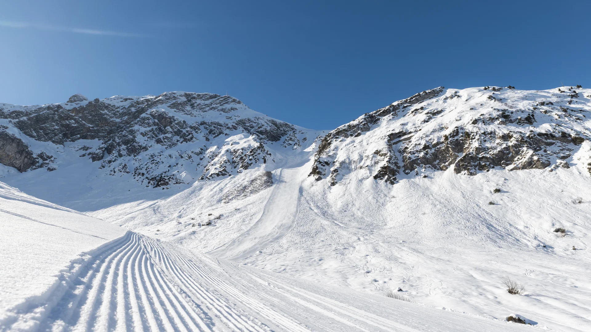 Picture gallery | Hotel Panorama in Lech am Arlberg Groomed ski slope winds through snowy mountains beneath a clear blue sky