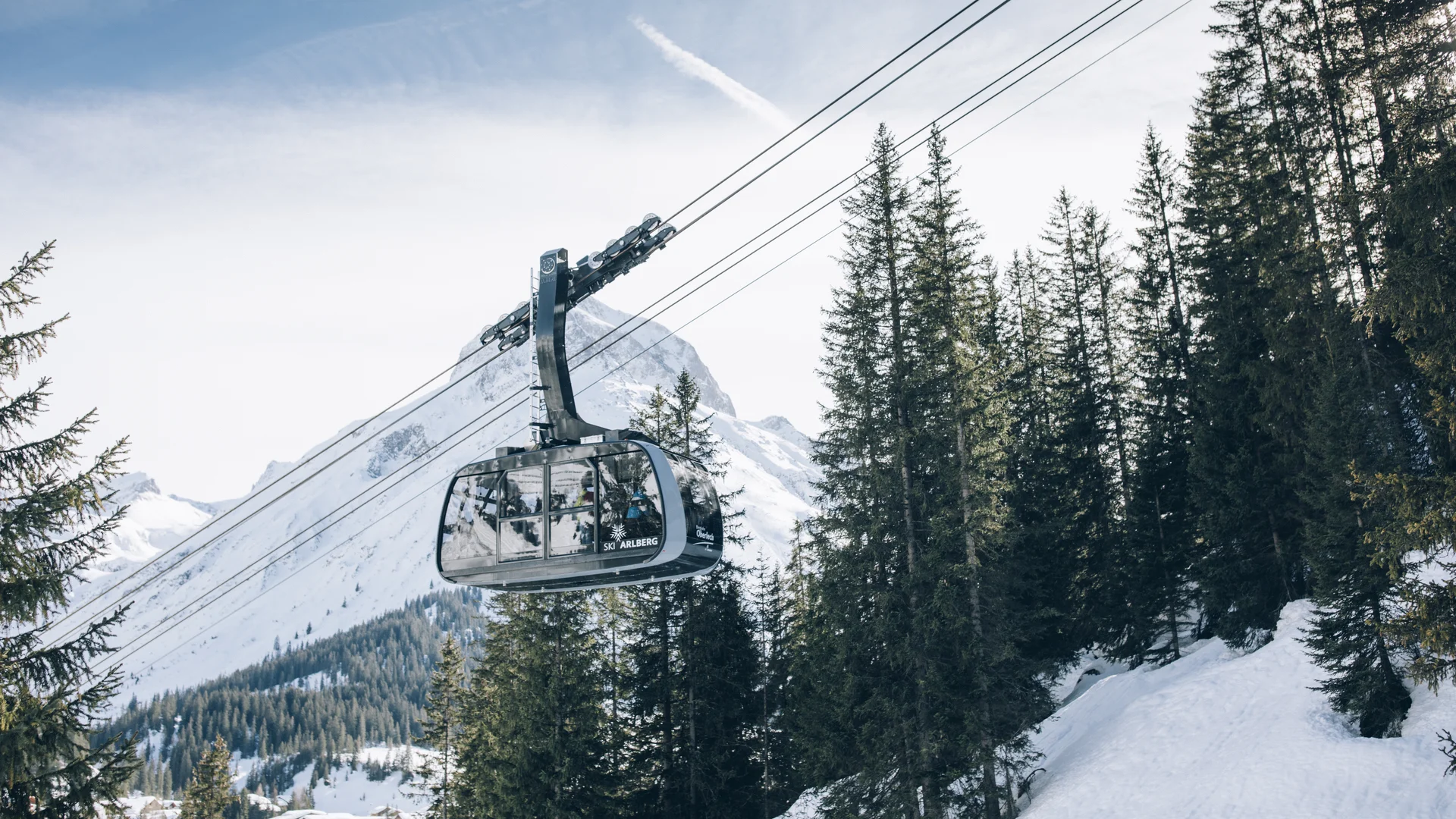 A ski holiday in Lech at Hotel Panorama Cable car above snow-covered fir trees with an alpine mountain backdrop