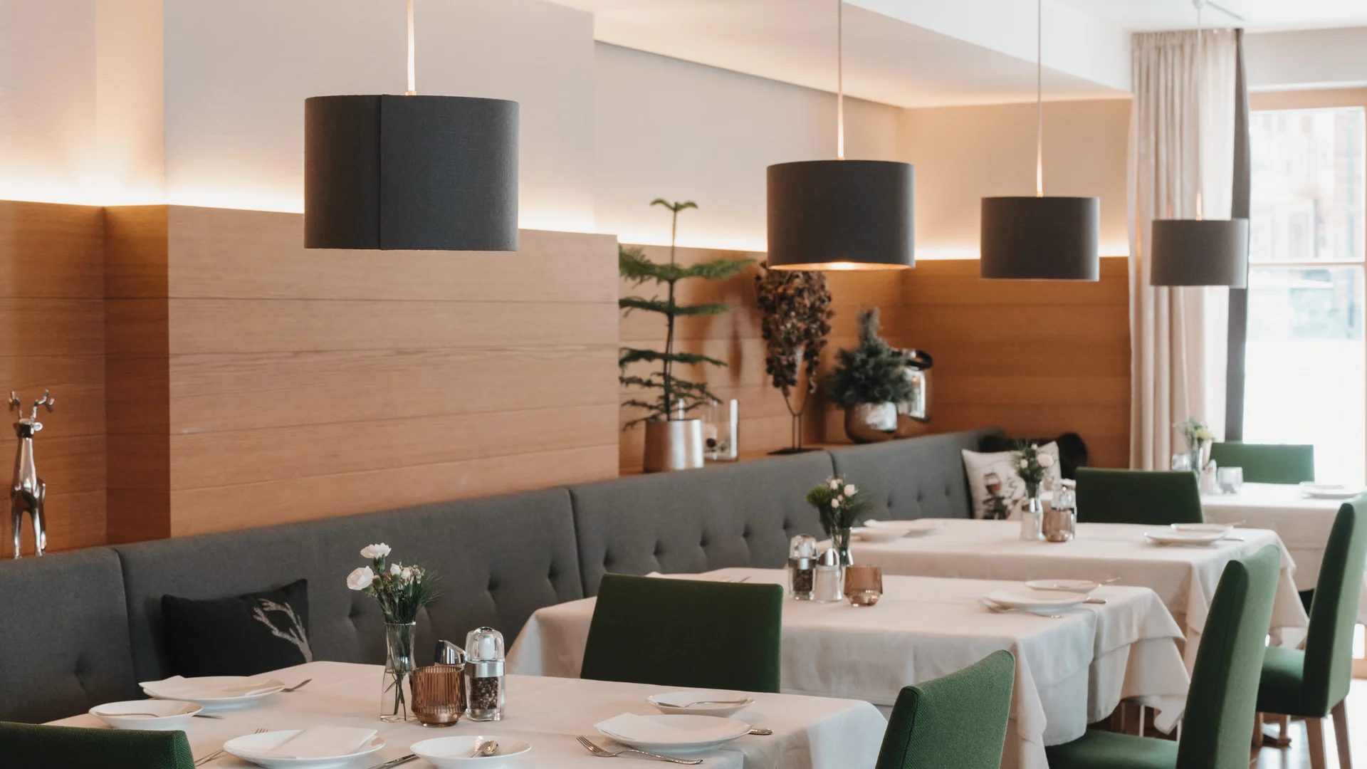 Picture gallery | Hotel Panorama in Lech am Arlberg Elegant dining room with white-clothed tables, green chairs and pendant lights