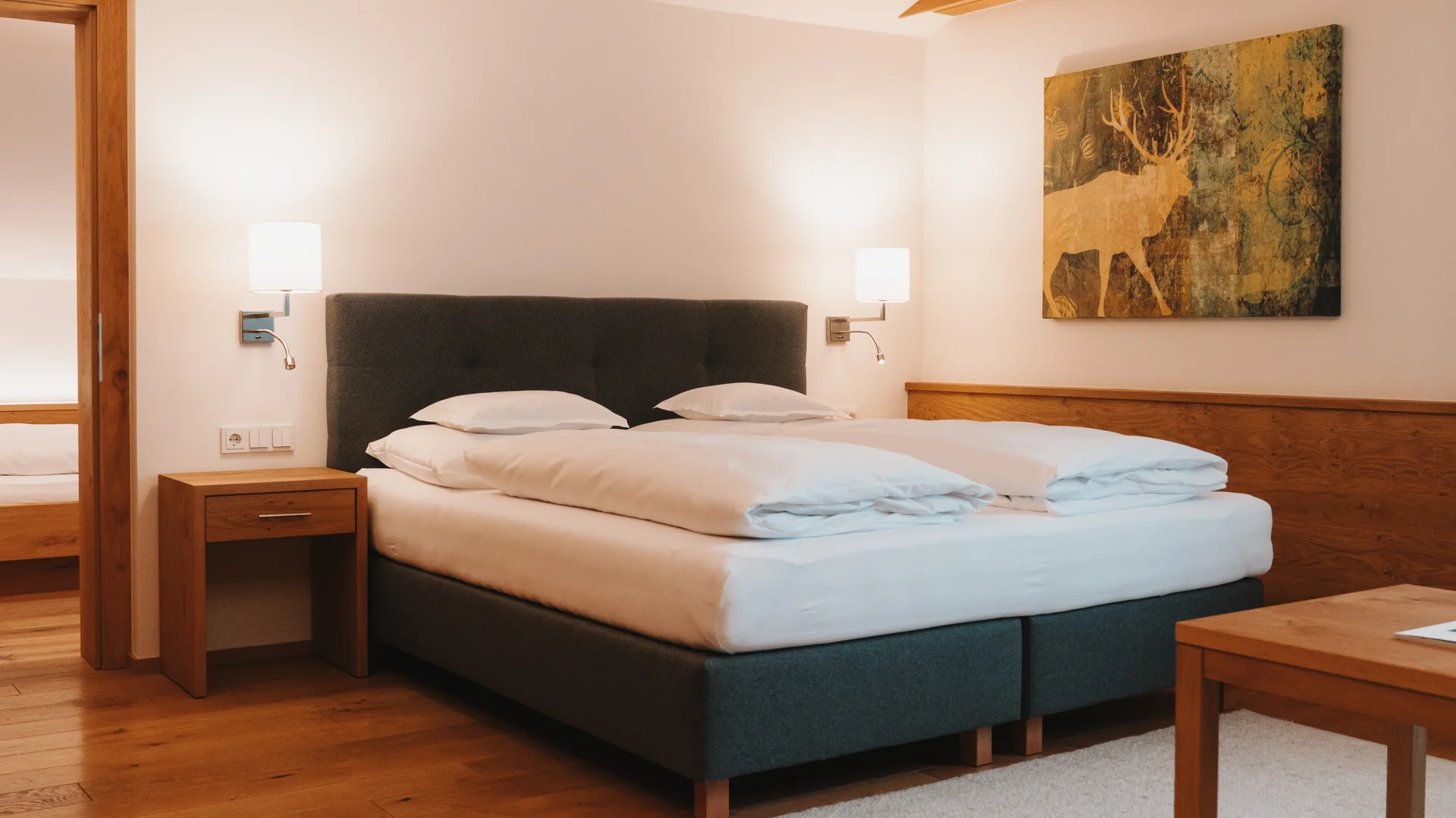 Picture gallery | Hotel Panorama in Lech am Arlberg Bright bedroom with a double bed, wooden floor, rug and wall art