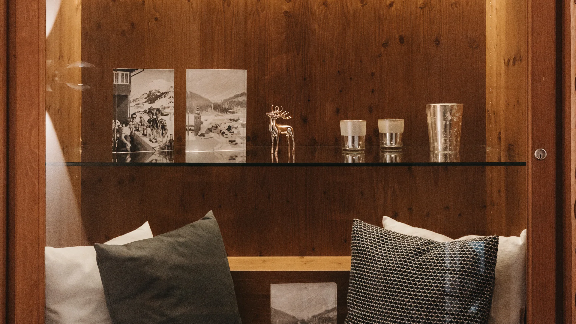 Picture gallery | Hotel Panorama in Lech am Arlberg Illuminated wooden cabinet with photos, a deer figurine, glasses and cushions