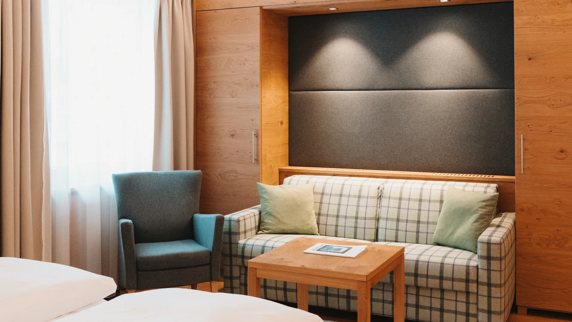 Picture gallery | Hotel Panorama in Lech am Arlberg Hotel room with a double bed, checked sofa, armchair and wooden furniture
