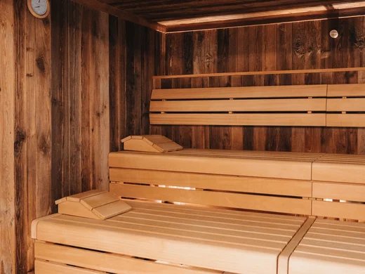 Holzsauna mit mehreren Sitzbänken und einer Uhr an der Wand