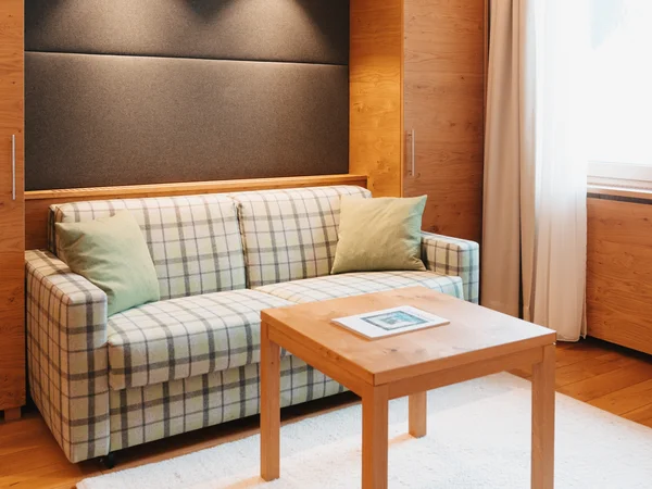 Inclusive services | Hotel Panorama in Lech am Arlberg Living area with a plaid sofa, wooden table and bright furnishings