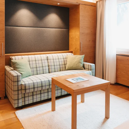 Inclusive services | Hotel Panorama in Lech am Arlberg Living area with a plaid sofa, wooden table and bright furnishings