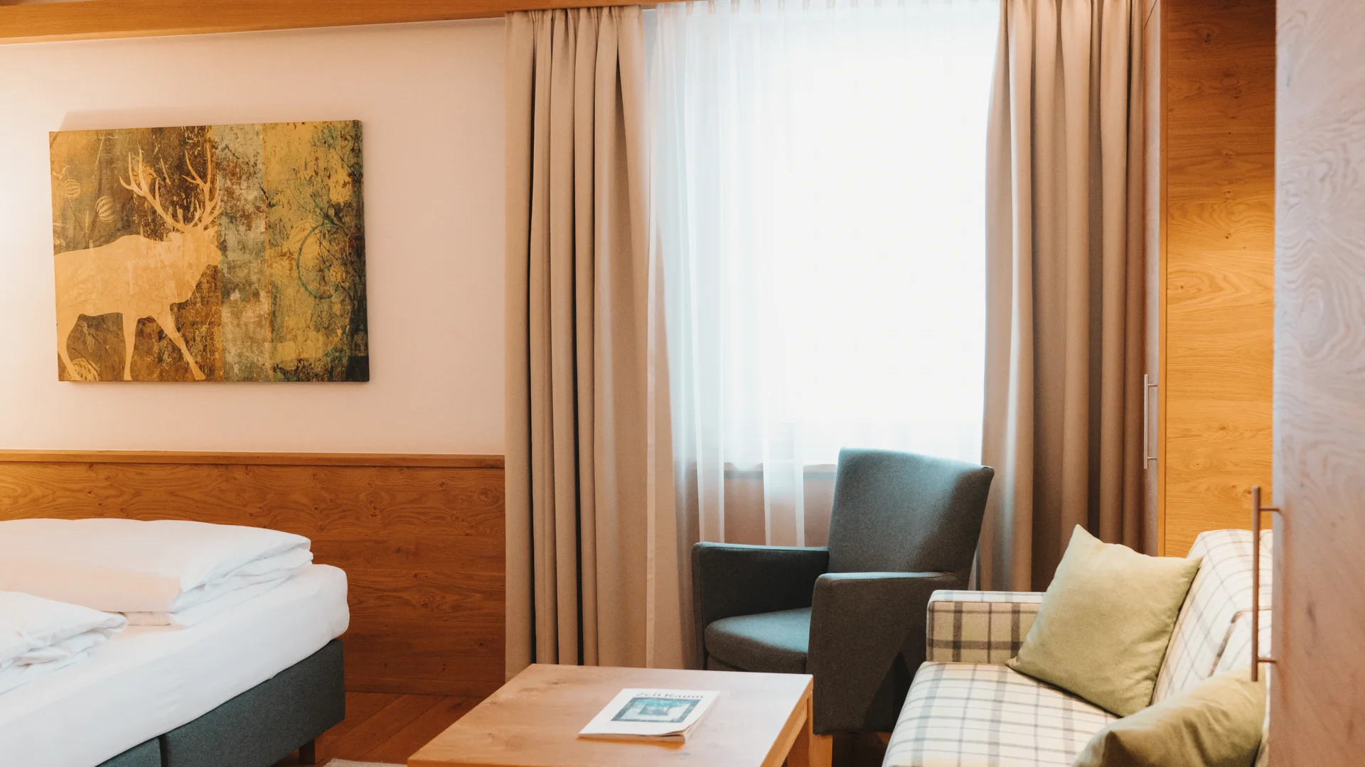 Picture gallery | Hotel Panorama in Lech am Arlberg Hotel room with a double bed, plaid sofa, armchair and wooden table