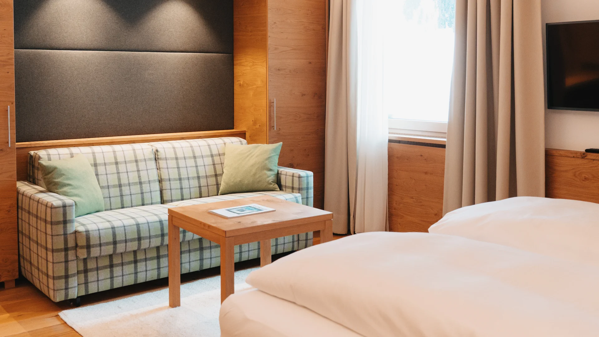 Picture gallery | Hotel Panorama in Lech am Arlberg Hotel room with a large bed, plaid sofa and wooden coffee table