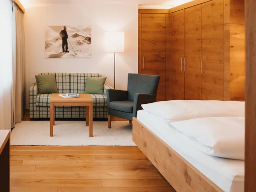 Hotel am Arlberg mit Aussicht | Hotel Panorama Lech Hotelzimmer mit Holzbett, Einbauschrank und Sitzecke mit Sofa und Sessel