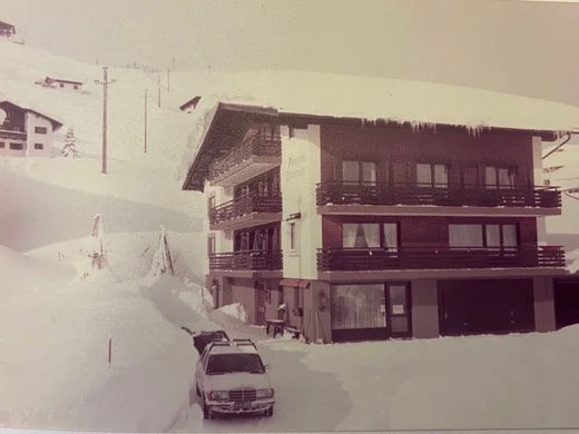 Family-run hotel in Austria | Hotel Panorama Snow-covered multi-story alpine house with balconies and a car in the foreground