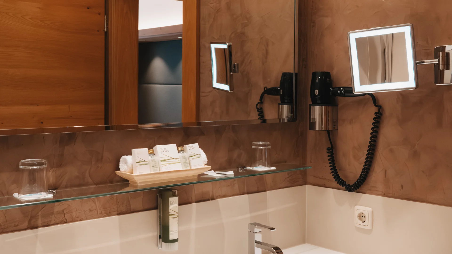 Picture gallery | Hotel Panorama in Lech am Arlberg Bathroom with a double vanity, large mirror, toiletries and a wall-mounted hairdryer