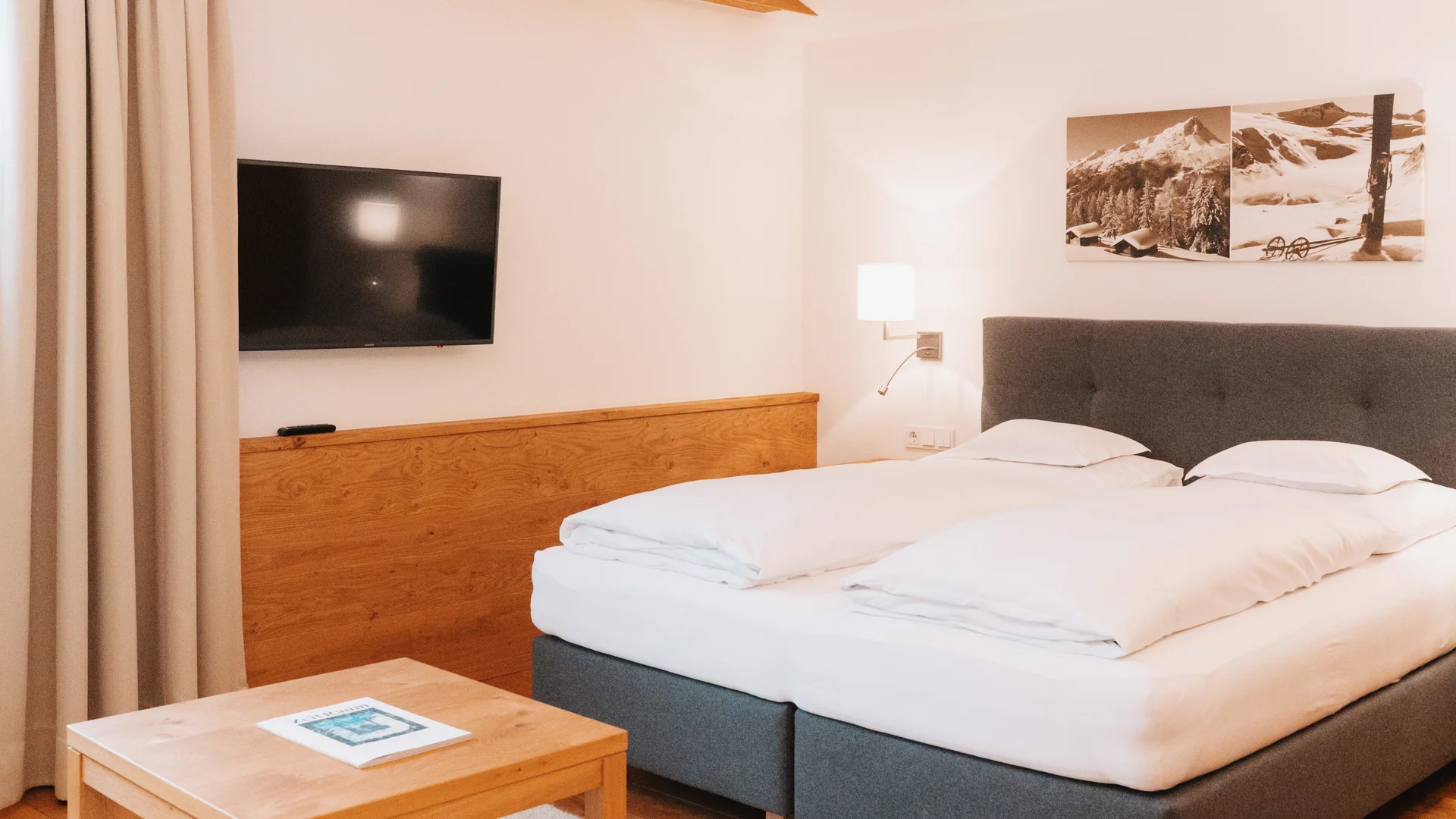 Picture gallery | Hotel Panorama in Lech am Arlberg Bright hotel room with a double bed, TV, wooden table and white rug