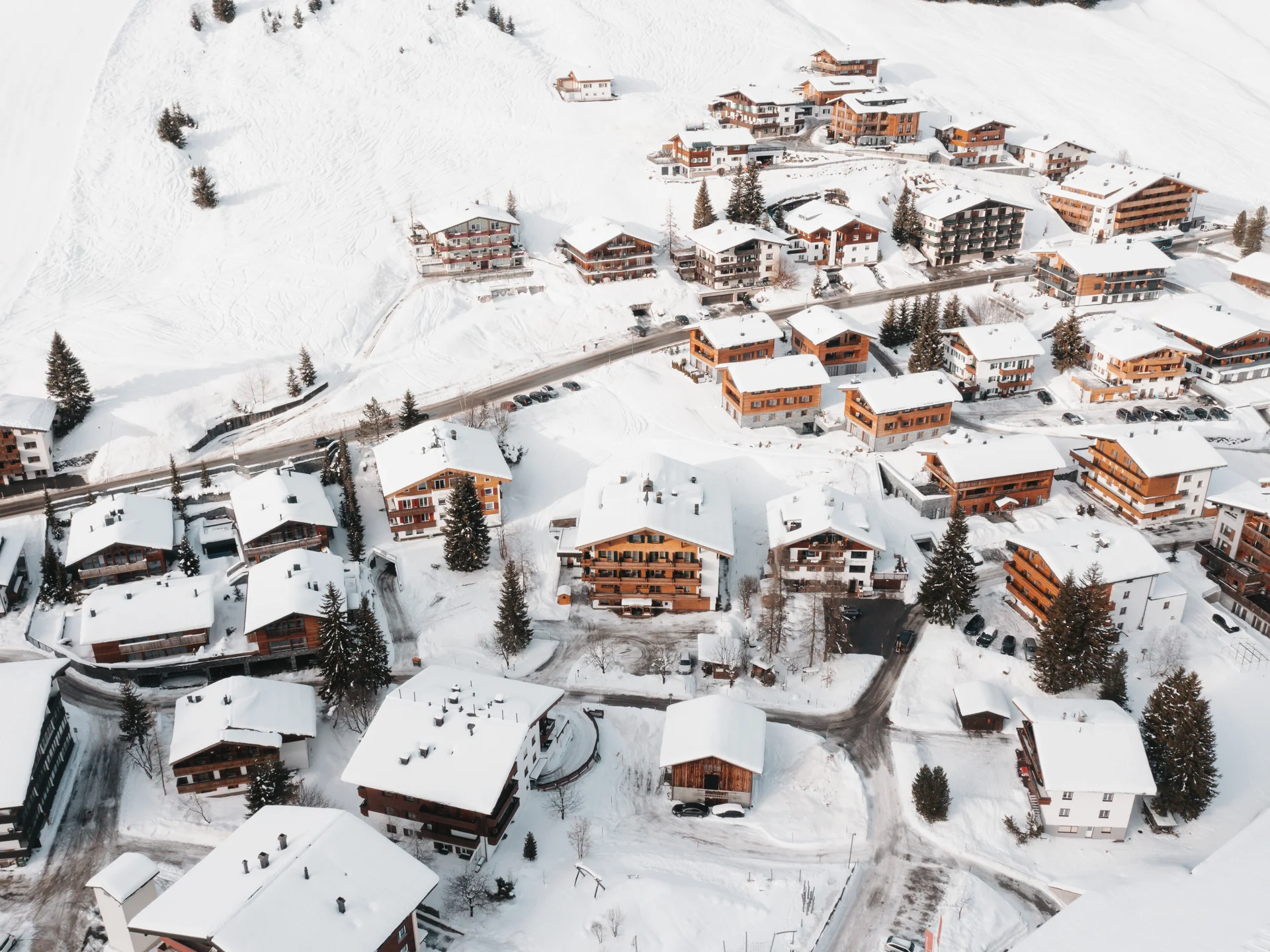 The journey to your hotel in Vorarlberg | Hotel Panorama Aerial view of a snow-covered mountain village with houses and roads