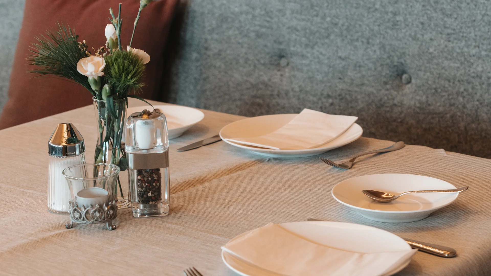 Picture gallery | Hotel Panorama in Lech am Arlberg Set dining table with plates, cutlery and flowers in front of an upholstered bench