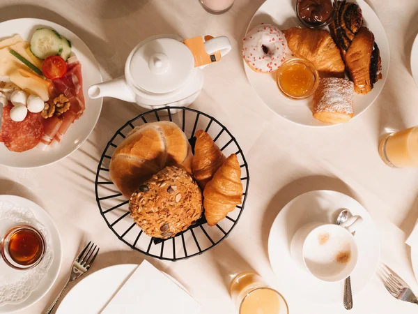 Inclusive services | Hotel Panorama in Lech am Arlberg Breakfast spread with bread, croissants, pastries, cold cuts, cheese, tea, coffee and juice