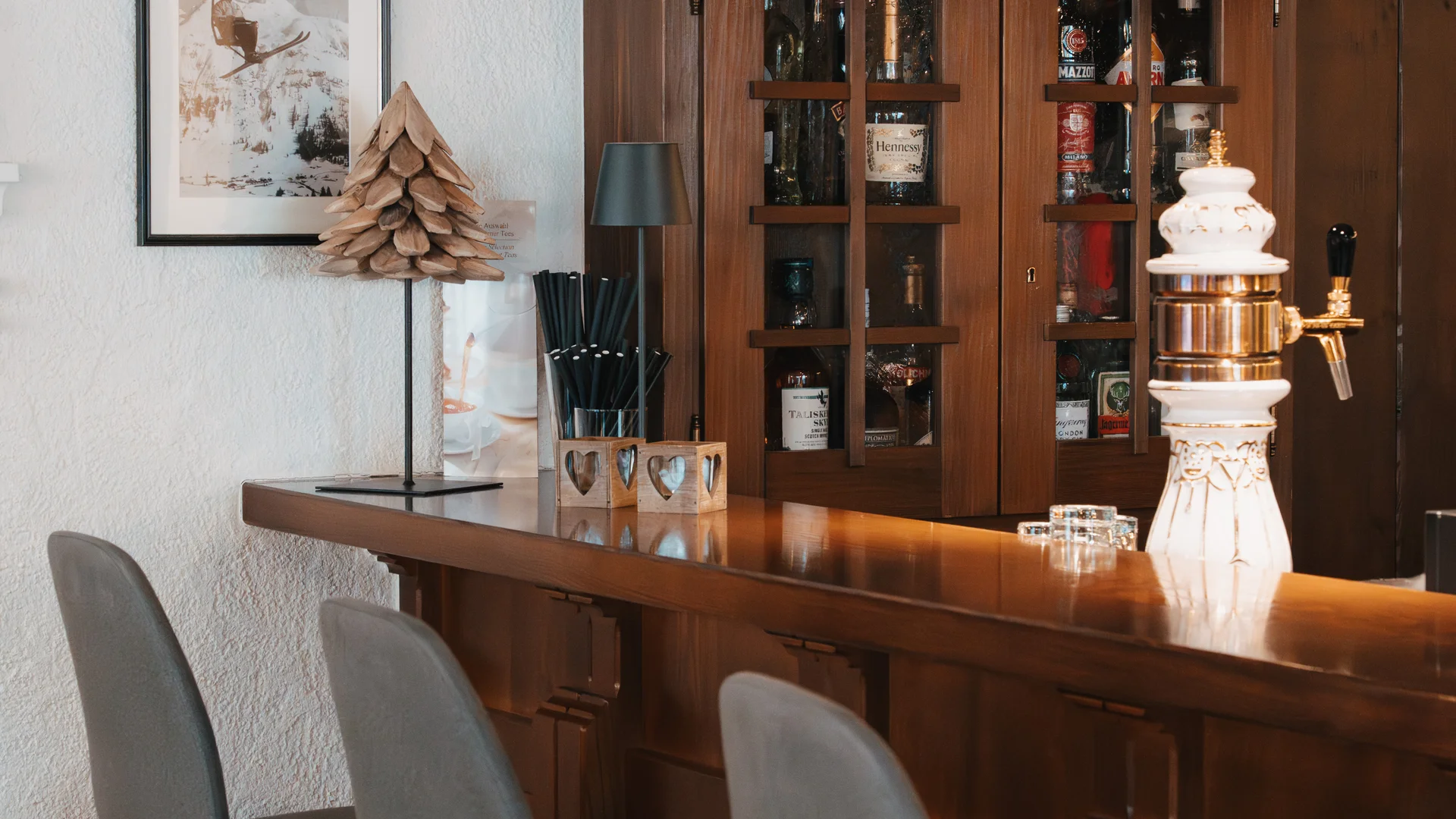Picture gallery | Hotel Panorama in Lech am Arlberg Rustic hotel bar with three gray bar stools and glasses on a wooden shelf
