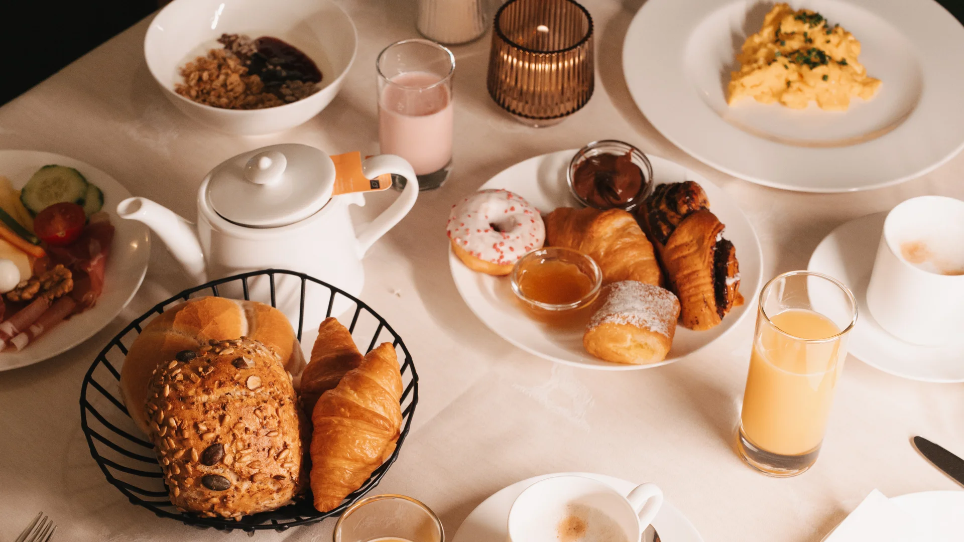 Breakfast table with pastries, eggs, cereal, juice and a vase of flowers