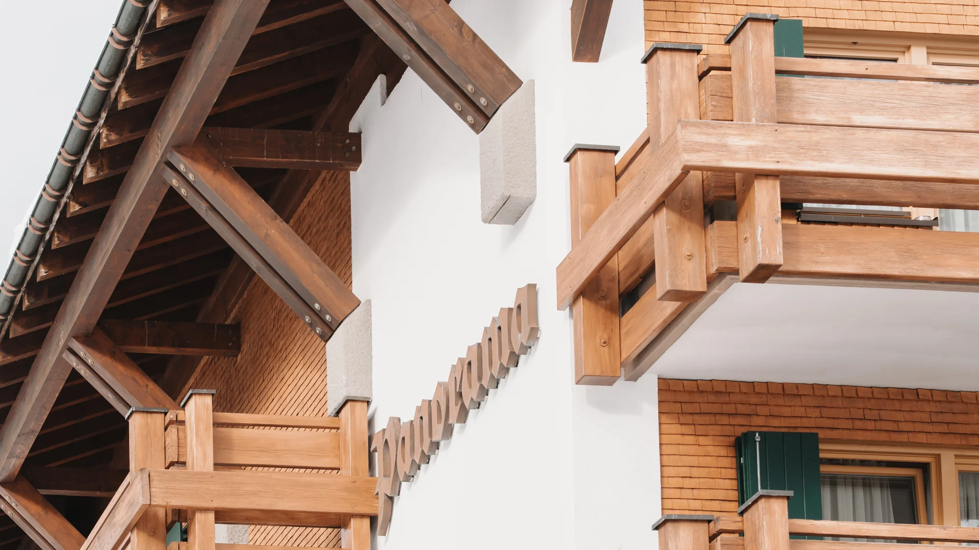 Picture gallery | Hotel Panorama in Lech am Arlberg Close-up of a building with wooden balconies, brick cladding and a wide overhanging roof